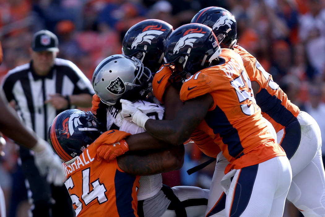 Oakland Raiders running back Marshawn Lynch (24) is tackled by Denver Broncos linebacker Brandon Marshall (54), linebacker Todd Davis (51) and others during the second half of their NFL game in D ...