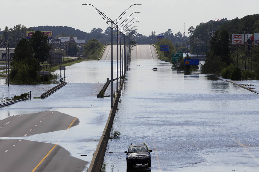FILE- In this Monday, Sept. 17, 2018, file photo flooded vehicles sit on a closed section of Interstate 95 in Lumberton, N.C., where the Lumber river overflowed following flooding from Hurricane F ...