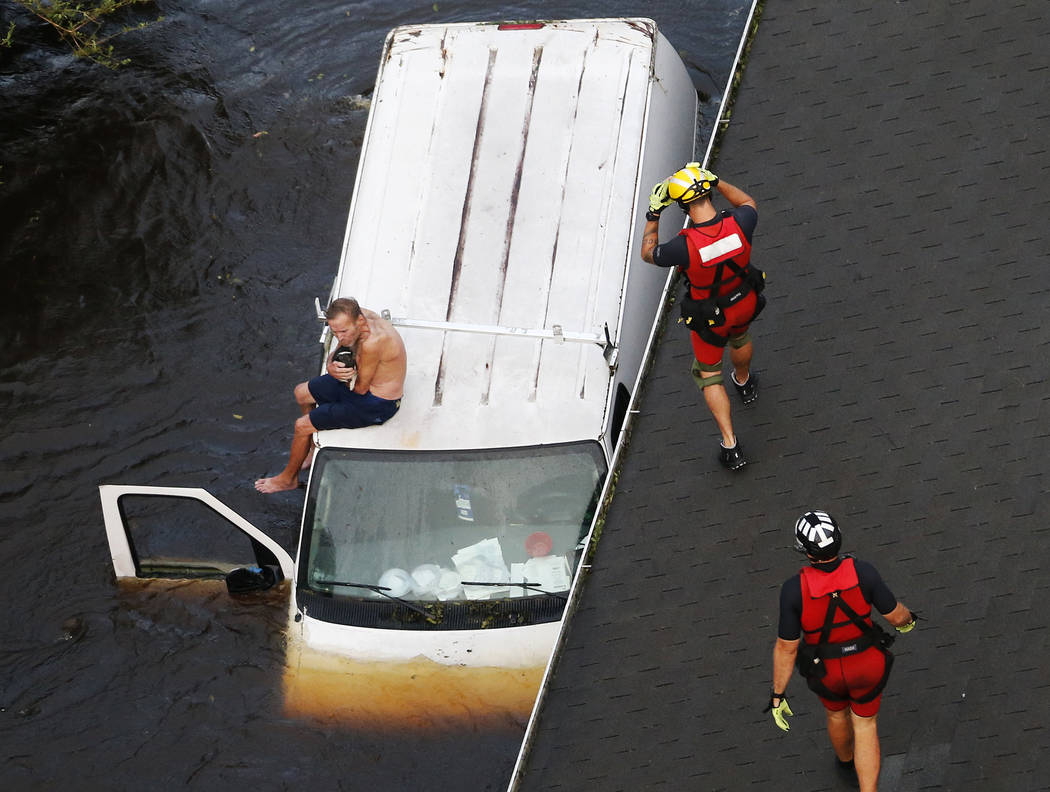 U.S. Coast Guard rescue swimmer Samuel Knoeppel, center, and Randy Haba, bottom right, approach to Willie Schubert of Pollocksville, N.C., on a stranded van in Pollocksville on Monday, Sept. 17, 2 ...