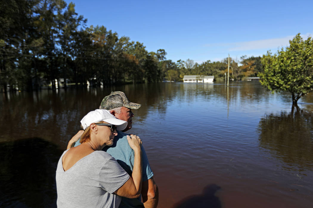 Dianna Wood, embraces her husband Lynn, as they look out over their flooded property as the Little River continues to rise in the aftermath of Hurricane Florence in Linden, N.C., Tuesday, Sept. 18 ...