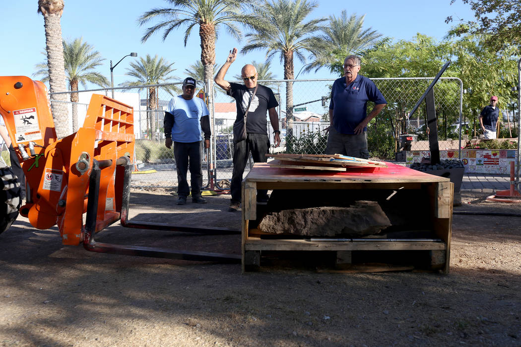 Jose Cernes, from left, artist Bobby Jacobs, center, and David Schember, oversee the moving of the base of a stone sculpture designed by Jacobs to the Healing Garden in Las Vegas, Thursday, Sept. ...