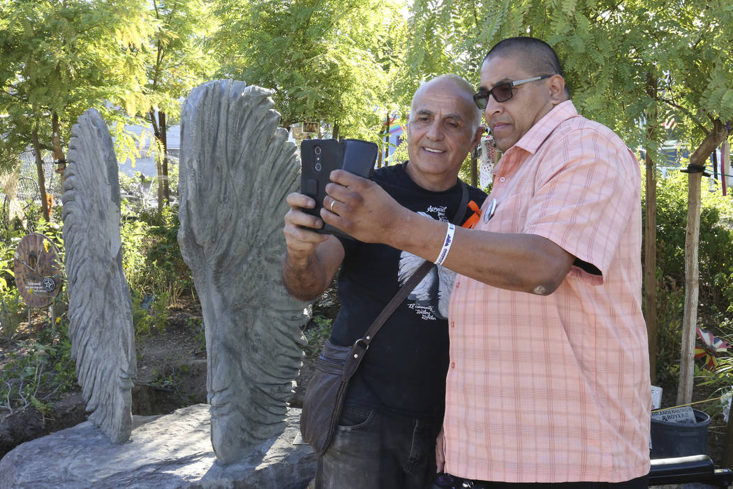 Bobby Jacobs, left, an artist from upstate New York, and Daniel Rosales, a survivor of the Oct. 1 shooting, take a selfie next to a sculpture, left, of two separate angel wings at the Las Vegas He ...