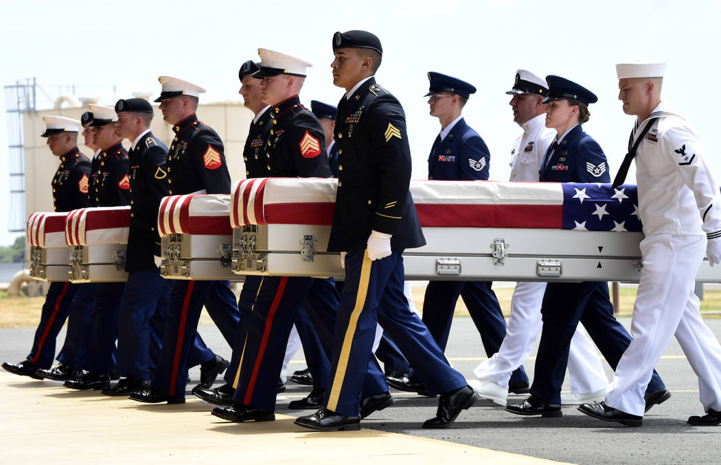 Military members carry transfer cases from a C-17 at a ceremony marking the arrival of the remains believed to be of American service members who fell in the Korean War at Joint Base Pearl Harbor- ...