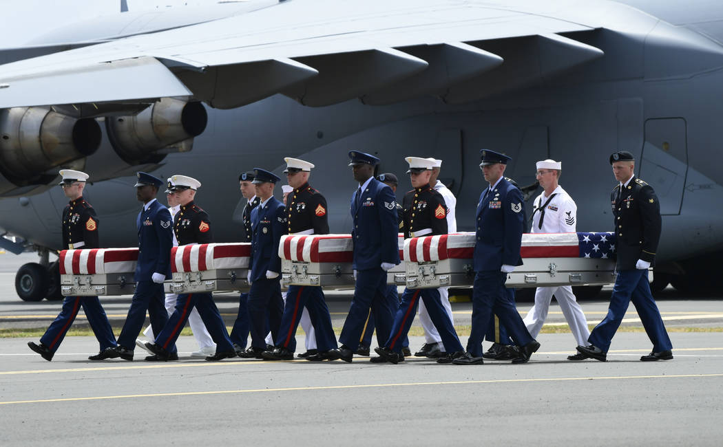 Military members carry transfer cases from a C-17 at a ceremony marking the arrival of the remains believed to be of American service members who fell in the Korean War at Joint Base Pearl Harbor- ...