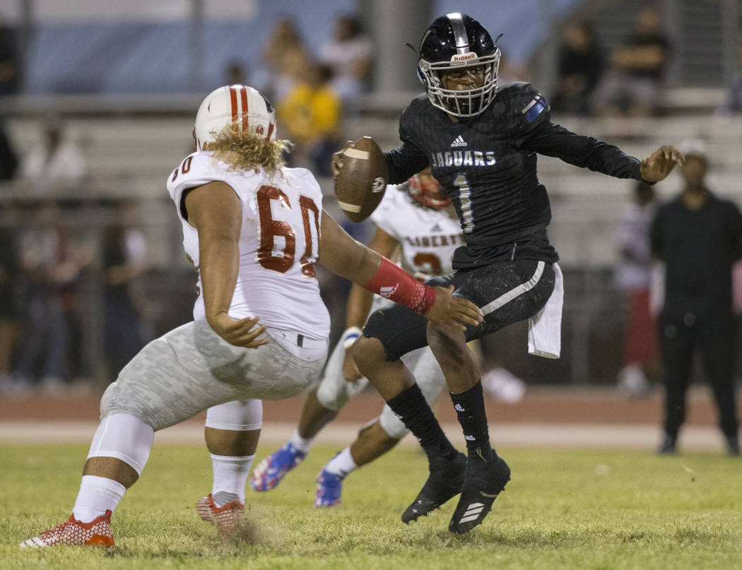 Desert Pines senior quarterback Tyler Williamson (1) makes a move past Liberty senior defensive tackle Xavier Fuamatu (60) in the first quarter during the Jaguars home game with the Patriots on Fr ...
