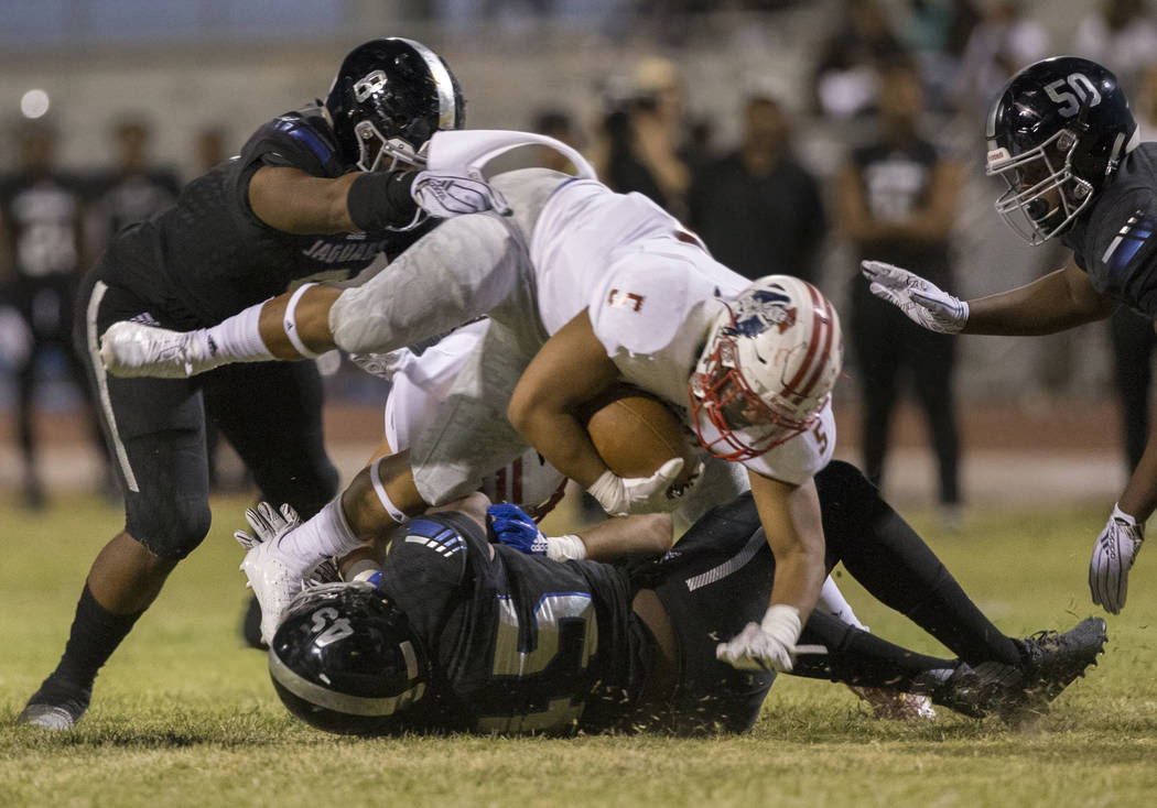 Liberty sophomore running back Ezra Tomhoon (5) leaps over Desert Pines senior defender Preston Williams (15) during the Patriots road game with the Jaguars on Friday, Sept. 21, 2018, at Desert Pi ...