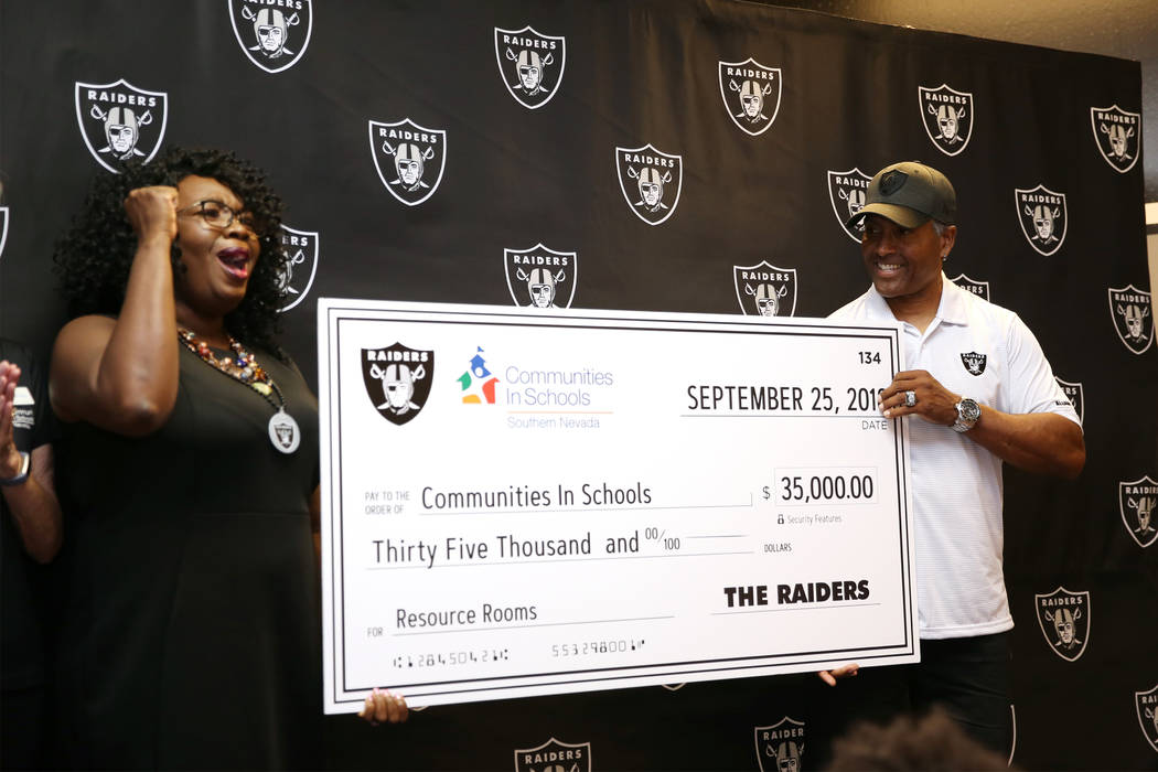 Tiffany Tyler, left, CEO of Communities in School of Nevada, reacts as Raiders alumni Leo Gray presents a donation of $35,000 during an event at Robert Taylor Elementary School in Henderson, Tuesd ...