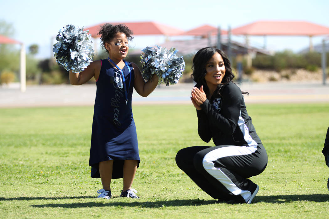 Third grade student Nevaeh Torregano, 8, left, cheers for her classmates with Raiderette Shaniah, during a Raiders youth football camp at Robert Taylor Elementary School in Henderson, Tuesday, Sep ...