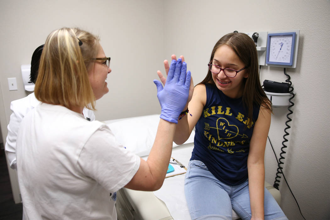 Natalia Ossa, 12, high fives medical assistant Lindsey Johnson after receiving a vaccine during a free back to school immunization and health clinic event hosted at the FirstMed Health and Wellnes ...