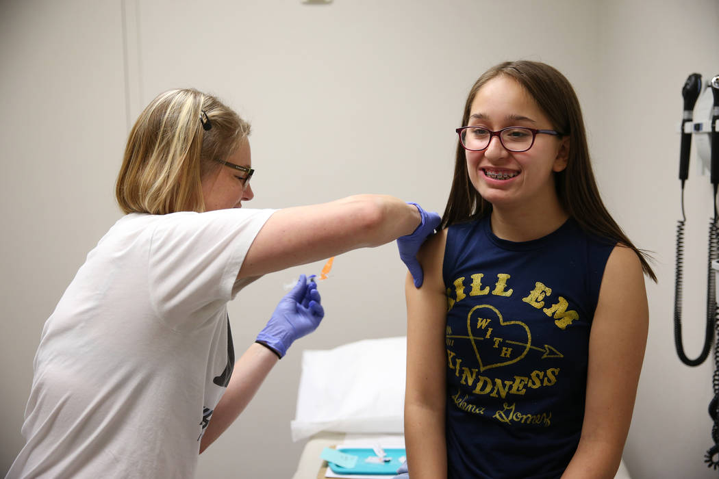 Natalia Ossa, 12, receives a vaccine from medical assistant Lindsey Johnson during a free back to school immunization and health clinic event hosted at the FirstMed Health and Wellness Center in L ...