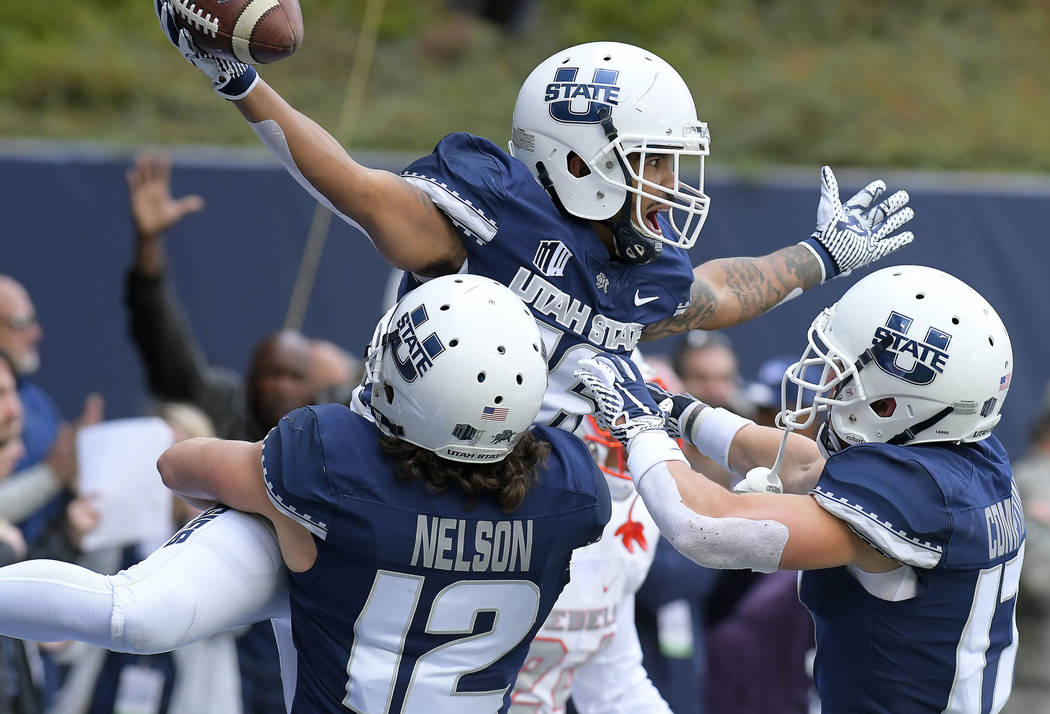 Utah State wide receiver Jordan Nathan (16) celebrates with teammates DJ Nelson (12) and Taylor Compton (17) after catching a 24-yard touchdown pass against UNLV during an NCAA college football ga ...