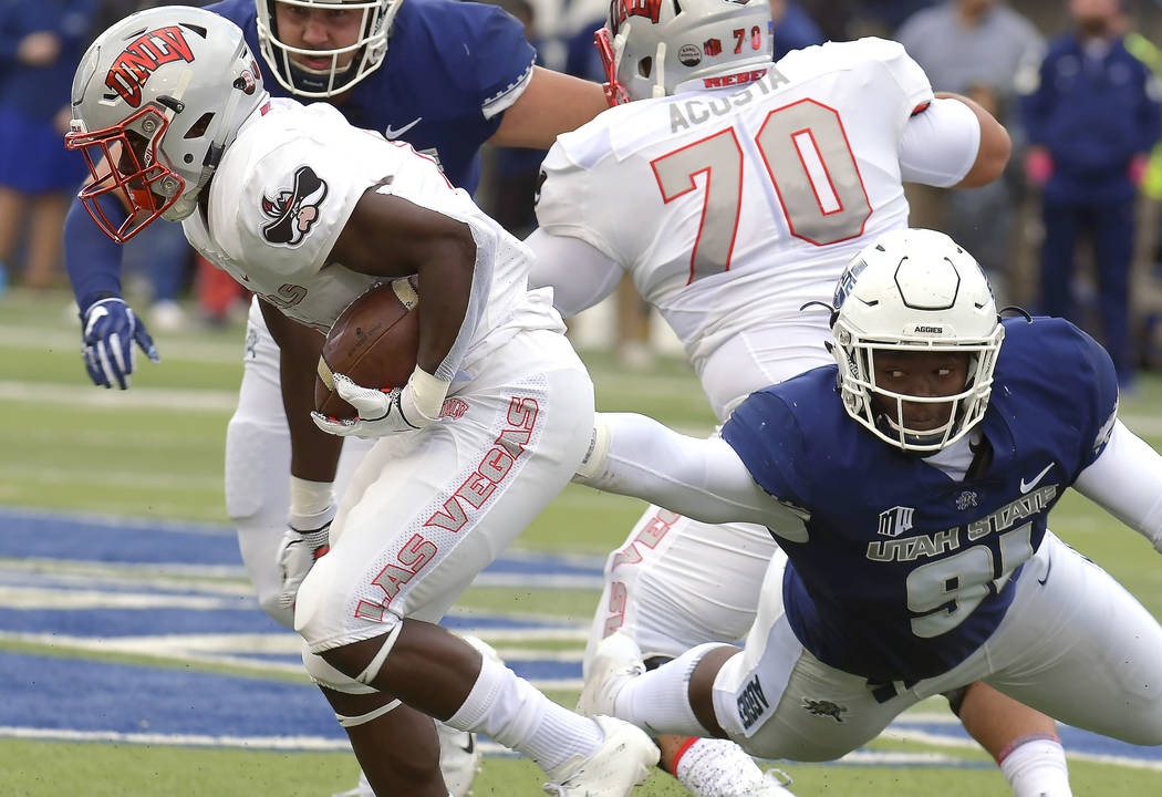 UNLV running back Charles Williams (8) carries the ball as Utah State defensive end Devon Anderson (91) reaches for him during an NCAA college football game Saturday, Oct. 13, 2018, in Logan, Utah ...