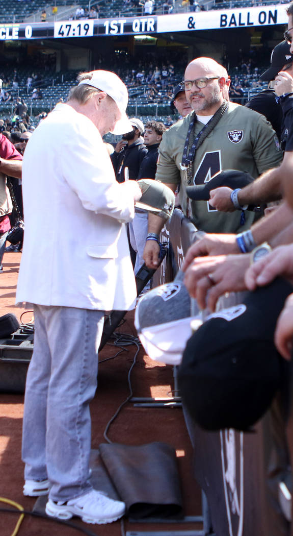 Oakland Raiders owner Mark Davis autographs a hat for Las Vegas Metro policeman Luciano Gonzalez in Oakland, Calif., Sunday, Sept. 30, 2018. First responders were invited to the game against the C ...