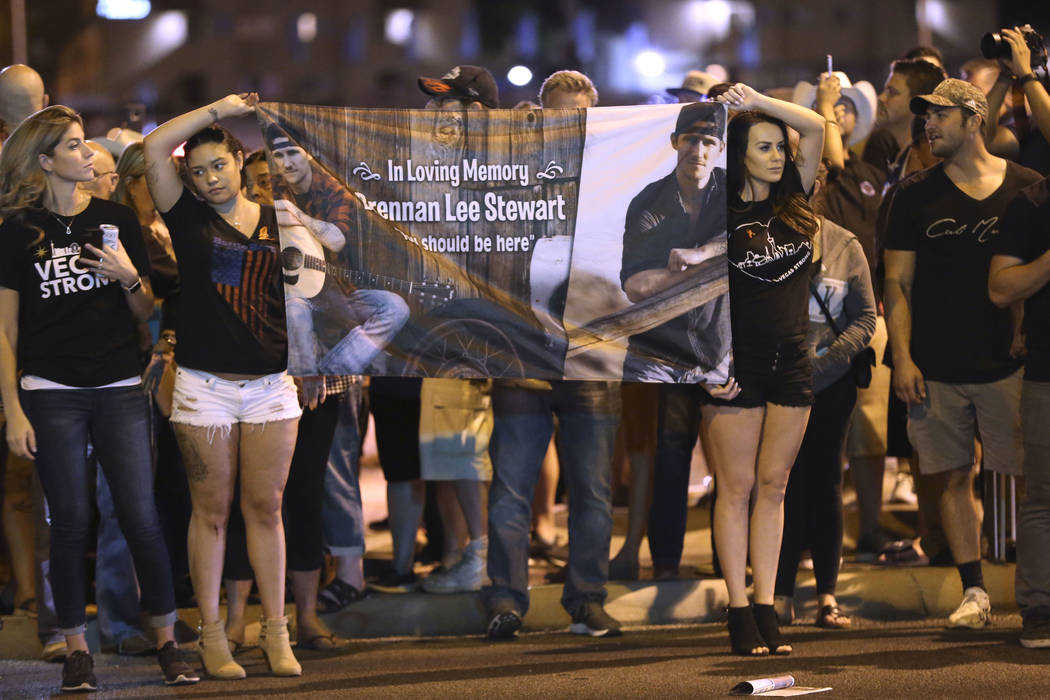 Cristina Armington, from left, Azjhree Lee and Lizzie Lee, all friends of Brennan Lee Stewart, who died in the Oct. 1 shooting, hold a banner in honor of Stewart outside Mandalay Bay hotel-casino ...