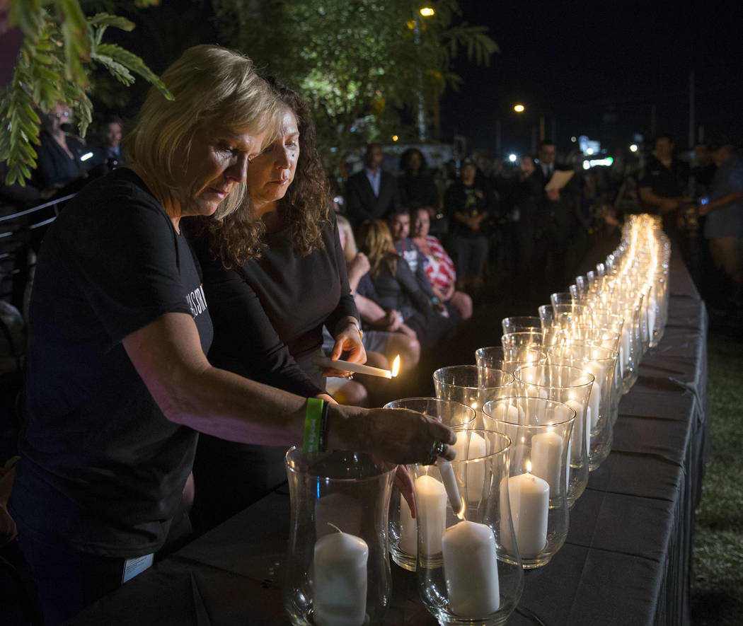 Esther Reincker, left, and Mauricia Baca light candles for the 58 victims of the Oct 1 shooting at 10:05 p.m., the exact time the shooting began last year, during a ceremony organized by the City ...