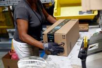 Myrtice Harris applies tape to a package before shipment at an Amazon fulfillment center in Bal ...