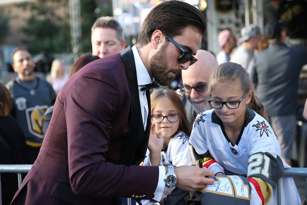 Vegas Golden Knights right wing Alex Tuch (89) signs an autograph for Rebecca Staskin, 10, far right ,with his sister Emma, 7, and father Michael of Las Vegas, before the Vegas Golden Knights seas ...
