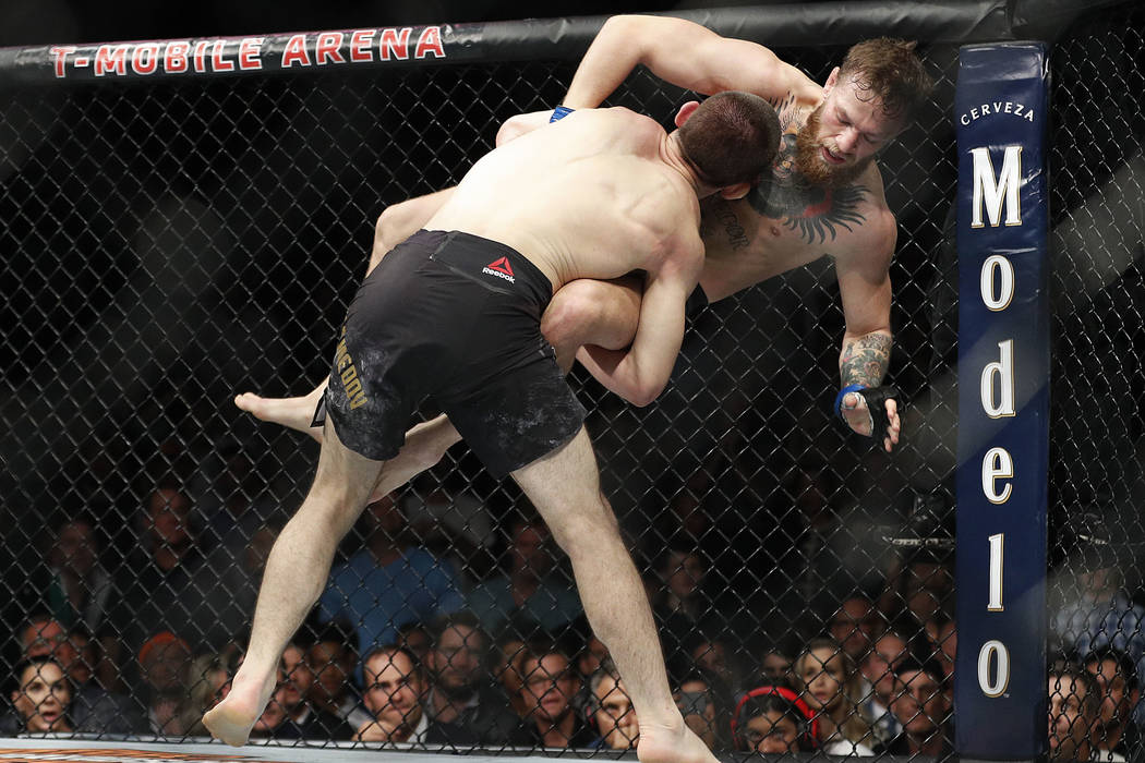 Khabib Nurmagomedov, left, takes down Conor McGregor during a lightweight title mixed martial arts bout at UFC 229 in Las Vegas, Saturday, Oct. 6, 2018. (AP Photo/John Locher)
