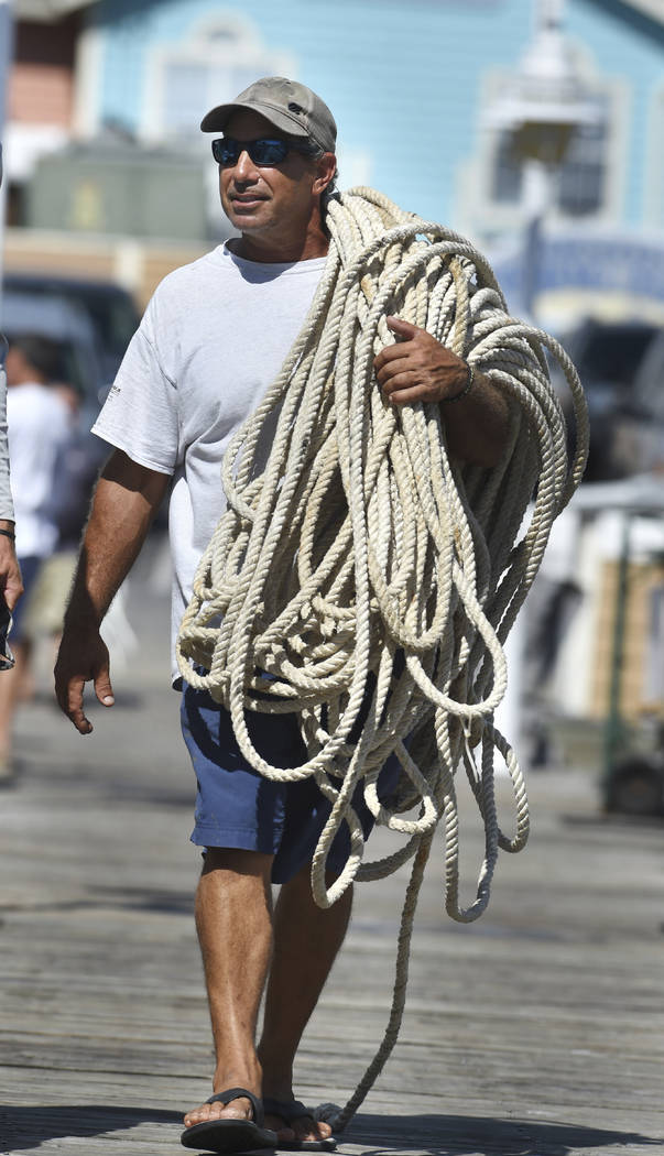 Aaron Smith carries a couple hundred feet of anchor rope as prepares to move his charter fishing boat "Sea Fix" from the Destin Harbor in Destin, Fla., on Monday, Oct. 8, 2018. Boat capt ...
