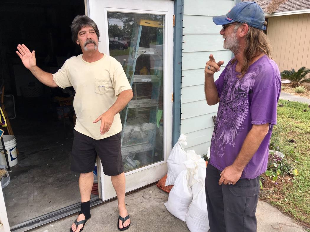 Dwight Williams, left, and Timothy Thomas discuss whether to evacuate their neighborhood in Panama City Beach, Fla., on Tuesday, Oct. 9, 2018. Thomas figures he and his wife will be safe from risi ...