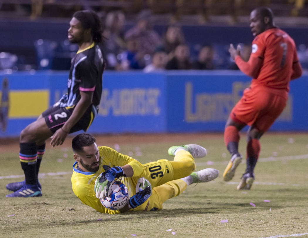 Las Vegas FC goalkeeper Thomas Olsen (30) makes a save against Phoenix Rising forward Billy Forbes (7) with the help of defender Joel Huiqui (3) in the first half during their United Soccer League ...