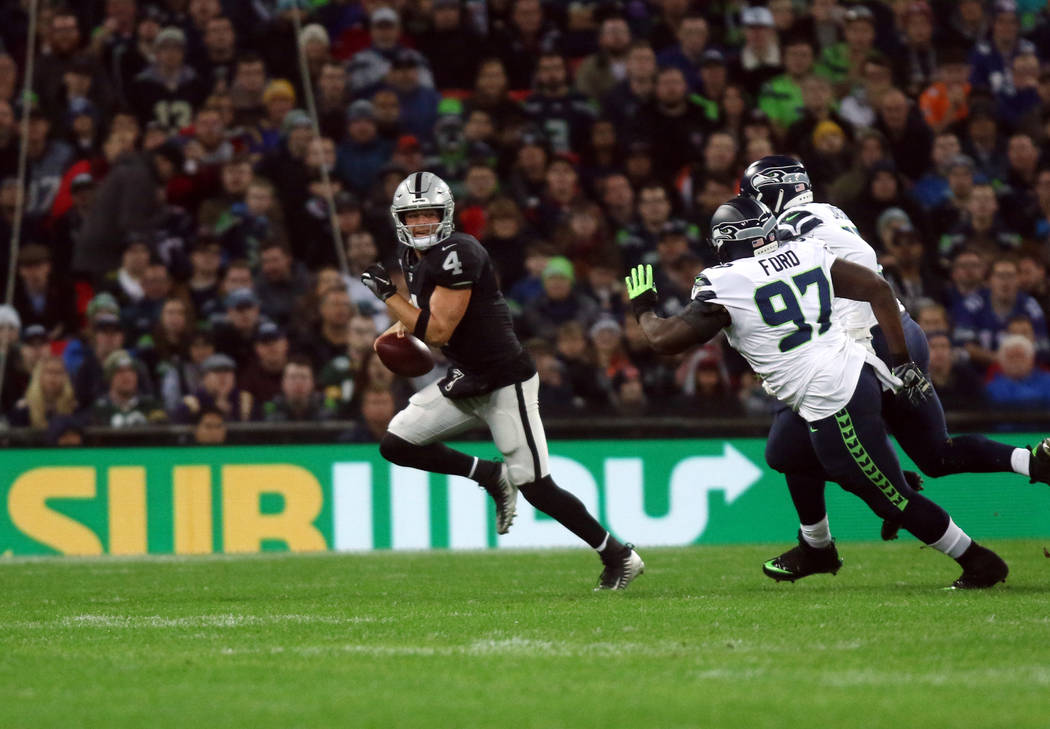 Oakland Raiders quarterback Derek Carr (4) scrambles with the football as Seattle Seahawks defensive tackle Poona Ford (97) and defensive end Frank Clark (55) pursue him during the first half of a ...