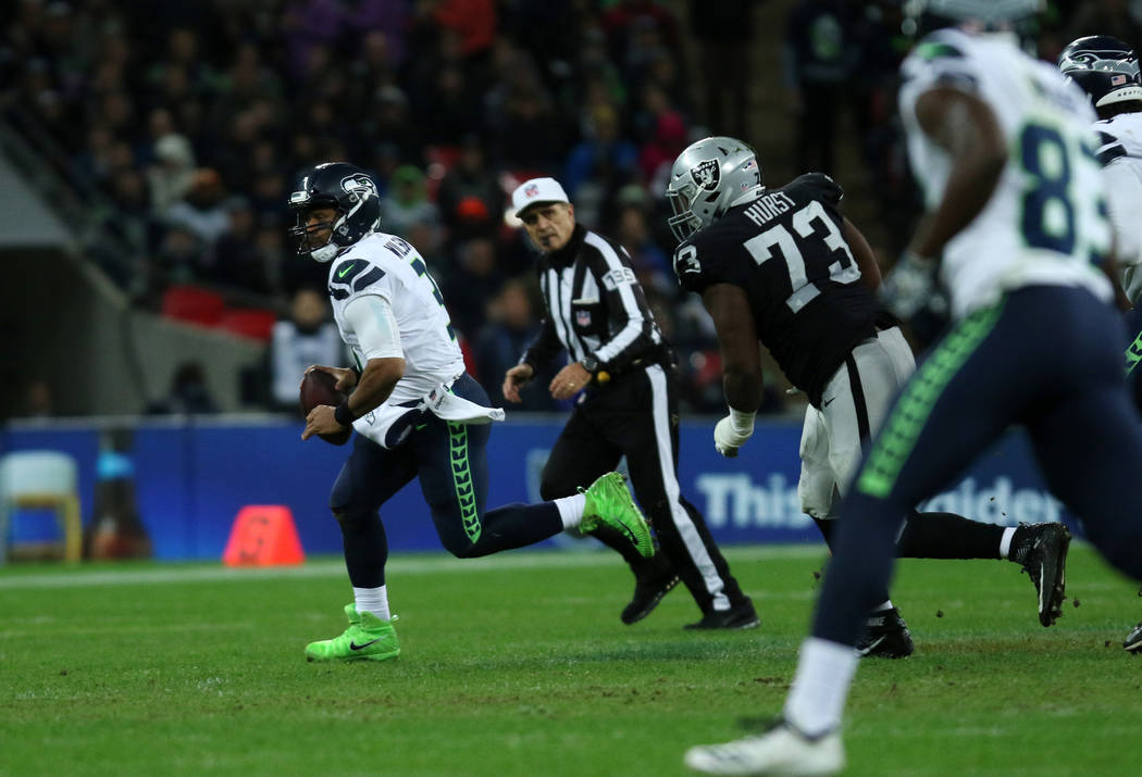 Seattle Seahawks quarterback Russell Wilson (3) scrambles with the football as Oakland Raiders defensive tackle Maurice Hurst (73) pursues him during the first half of an NFL game at Wembley Stadi ...