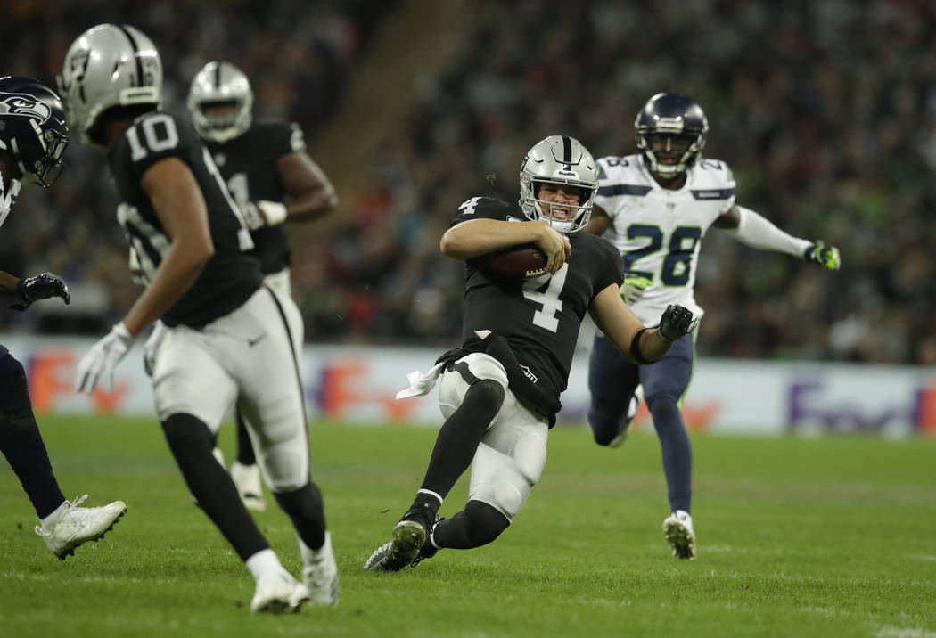 Oakland Raiders quarterback Derek Carr (4) slides after scrambling for yards during the first half of an NFL football game against Seattle Seahawks at Wembley stadium in London, Sunday, Oct. 14, 2 ...