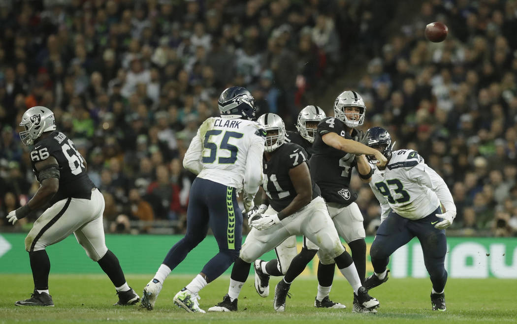 Oakland Raiders quarterback Derek Carr (4), second right, passes the ball during the first half of an NFL football game at Wembley stadium in London, Sunday, Oct. 14, 2018. (AP Photo/Matt Dunham)
