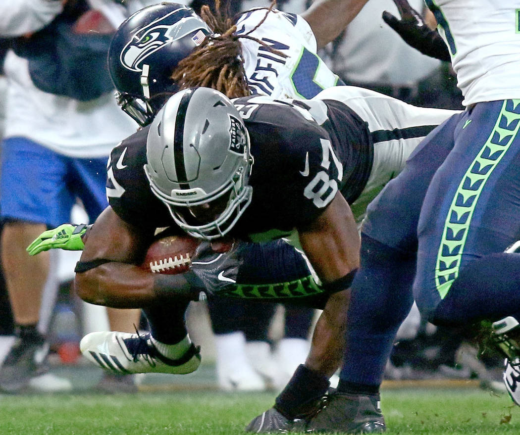 Oakland Raiders tight end Jared Cook (87) reaches for more yards as he's tackled by Seattle Seahawks cornerback Justin Coleman (28) during the first half of an NFL game at Wembley Stadium in Londo ...