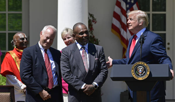 President Donald Trump, right, talks about Jon Ponder, second from right, from Las Vegas, and FBI Special Agent Richard Beasley, second from left, during a National Day of Prayer event in the Rose ...