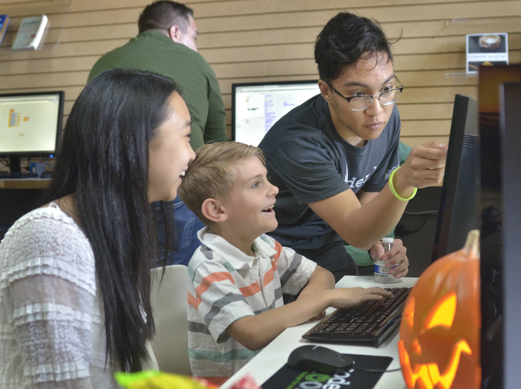 Code coach Tony DeLeon, right, is shown with Jessica Li, 17, left, of Henderson and Caleb Kays, 8, of Las Vegas during the grand opening of theCoderSchool at 9330 W. Sahara Ave. in Las Vegas on Sa ...