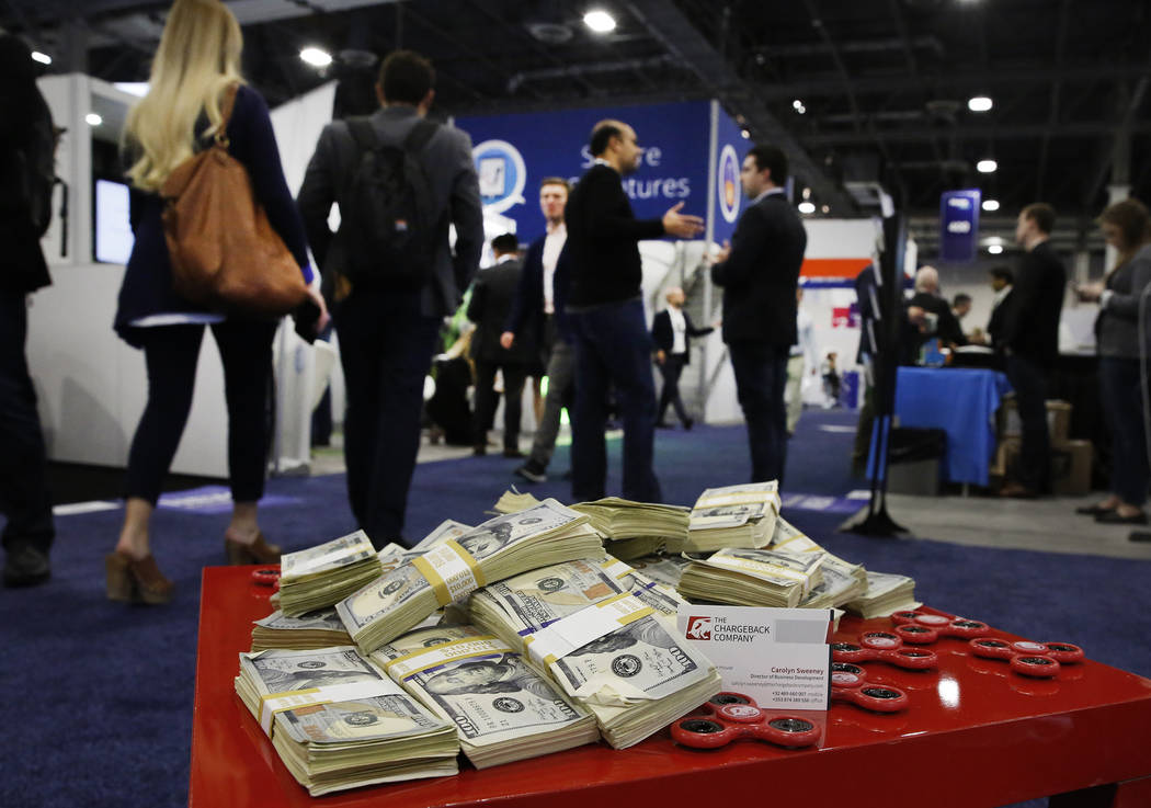 Attendees walk past fake paper play money during the 2017 Money 20/20 conference at the Sands Expo and Convention Center Monday, Oct. 23, 2017, in Las Vegas. Bizuayehu Tesfaye Las Vegas Review-Jou ...
