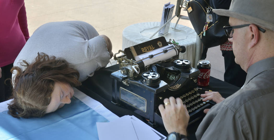Madison Greenstein, 15, of Henderson checks out the inner workings of a 1940s-era Royal typewriter through a window on its side as author Sean Hoade works on a haiku during the Las Vegas Book Fest ...