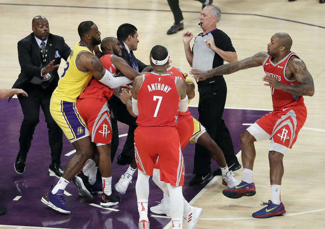 Houston Rockets' Chris Paul, second from left, is held back by Los Angeles Lakers' LeBron James, left, as Paul fights with Lakers' Rajon Rondo, center obscured, during the second half of an NBA ba ...