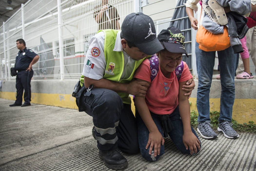 A Honduras migrant is comforted by a Mexican paramedic after her mother fainted while crossing the border between Guatemala and Mexico, in Ciudad Hidalgo, Mexico, Saturday, Oct. 20, 2018. Mexican ...