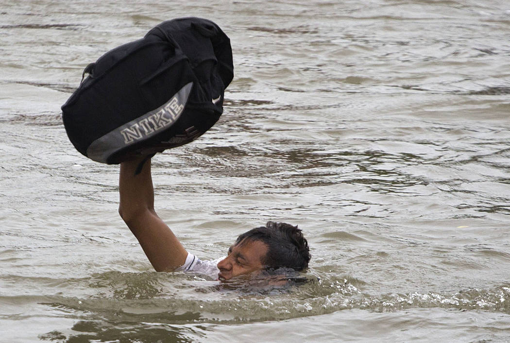 A Central American migrant wades across the Suchiate River, on the the border between Guatemala and Mexico, in Ciudad Hidalgo, Mexico, Saturday, Oct. 20, 2018. After Mexican authorities slowed acc ...