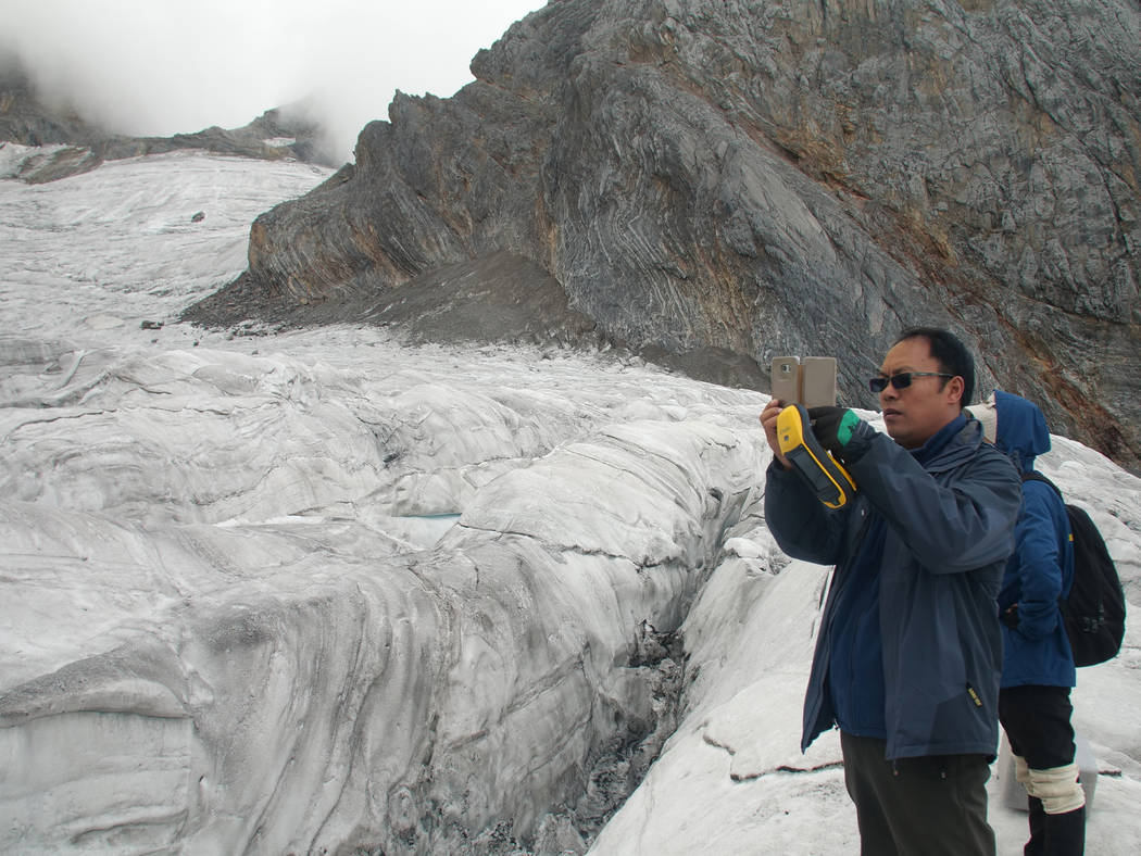 This Sept. 22, 2018 photo shows glaciologist Wang Shijin photographing the Baishui Glacier No.1 on the Jade Dragon Snow Mountain in the southern province of Yunnan in China. Scientists say the gla ...