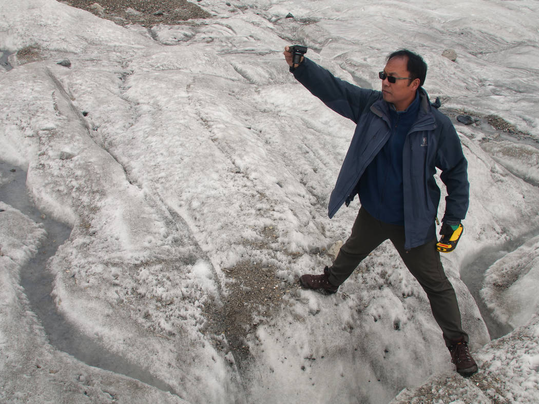 This Sept. 22, 2018 photo shows glaciologist Wang Shijin photographing an ice crevasse in the Baishui Glacier No. 1 on the Jade Dragon Snow Mountain in the southern province of Yunnan in China. Sc ...