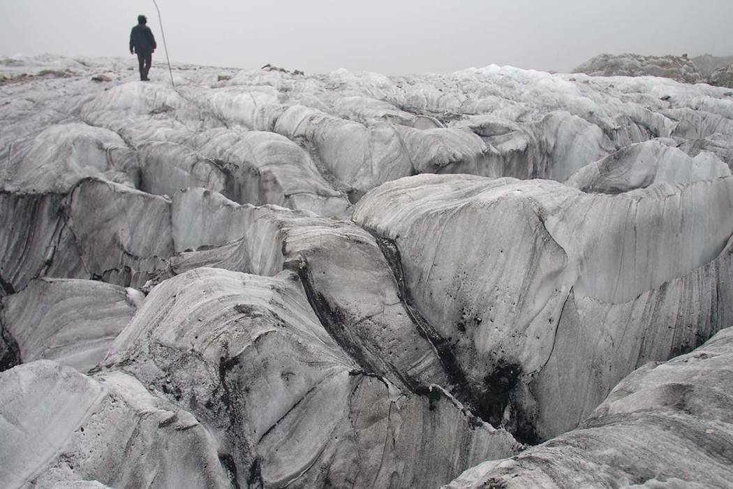 In this Sept. 22, 2018 photo, glaciologist Wang Shijin walks across the Baishui Glacier No.1 on Jade Dragon Snow Mountain in the southern province of Yunnan in China. Scientists say the glacier is ...