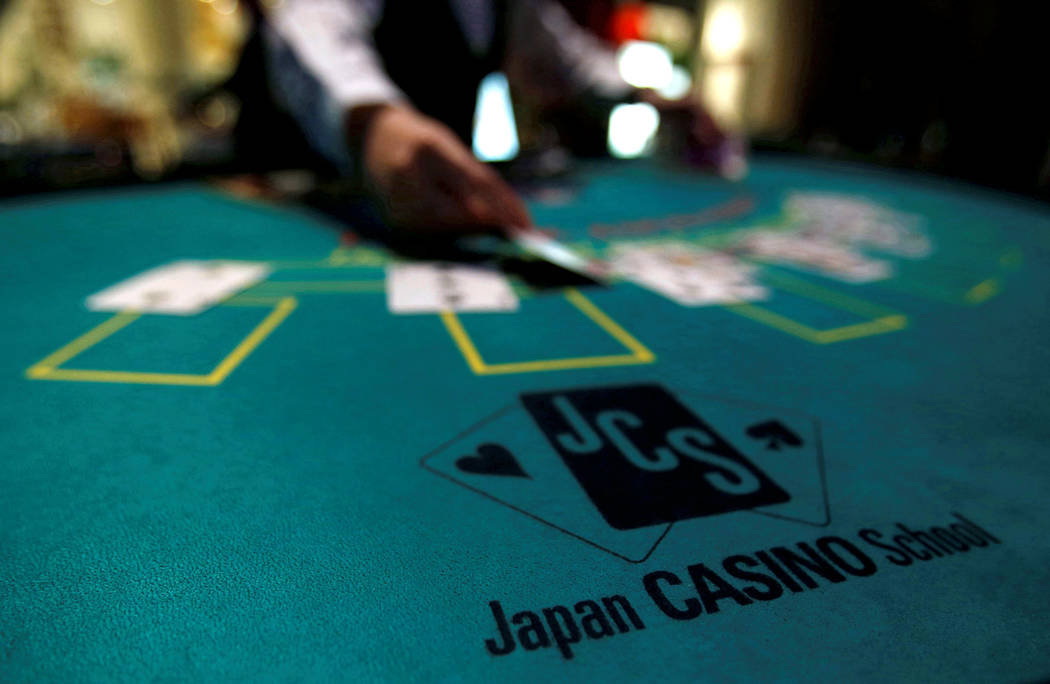 A logo of Japan casino school is seen as a dealer puts cards on a mock black jack casino table during a photo opportunity at an international tourism promotion symposium in Tokyo, Japan September ...