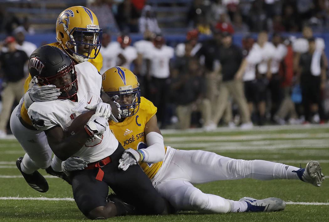 UNLV wide receiver Tyleek Collins, foreground, is tackled by San Jose State cornerback Dakari Monroe, right, and safety Jonathan Lenard Jr. during the second half of an NCAA college football game ...
