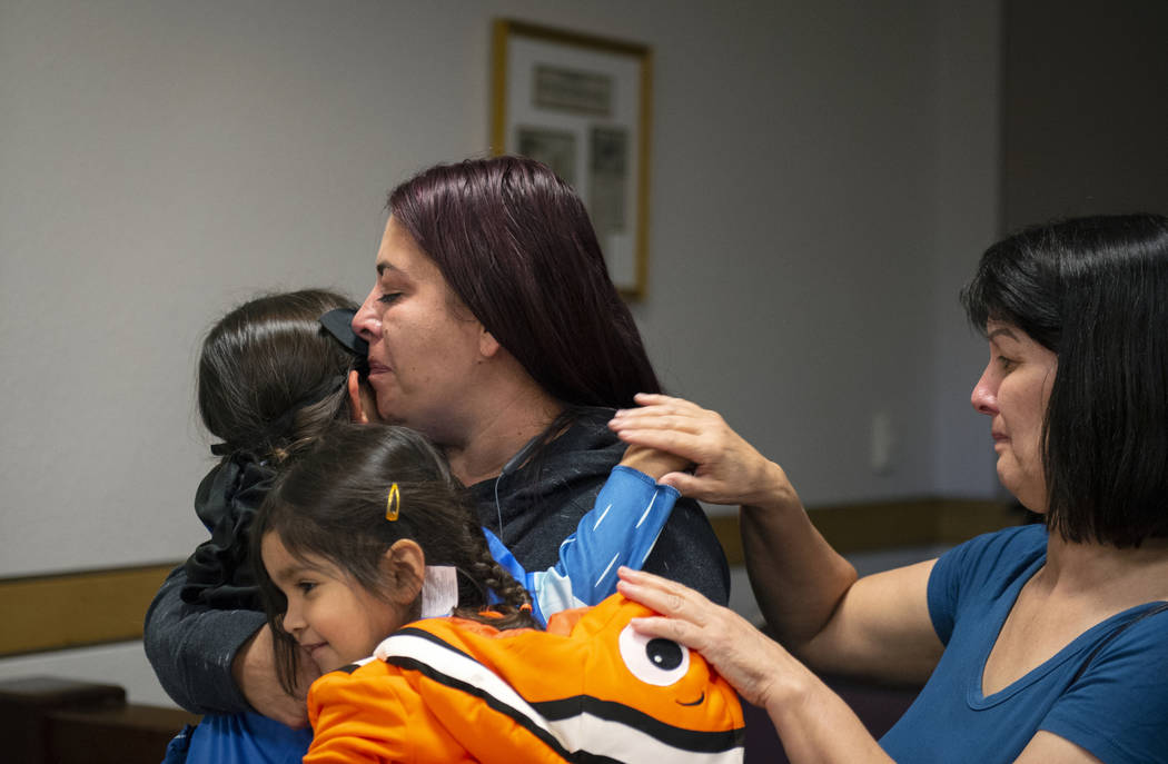 Dawn Hentzi holds her new adopted family member Ammerah, 6, while standing next to her other daughter Elia Raymond, 3, and her friend Patty Celis as they are sworn in by District Court Family Judg ...