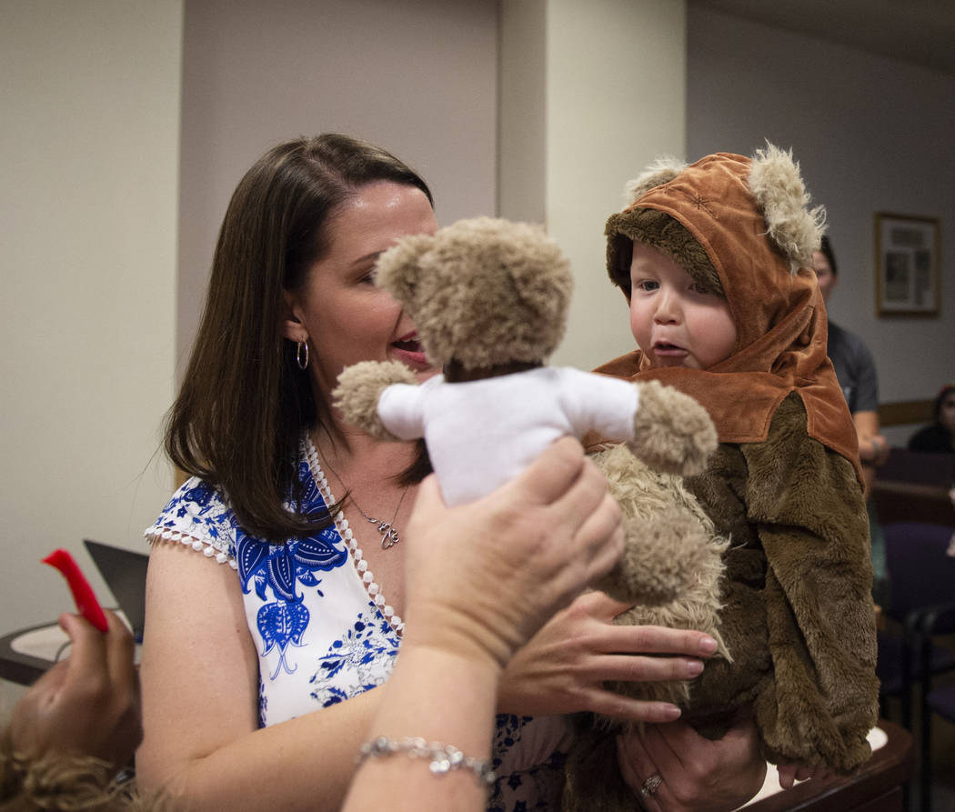 Julie Elliott holds new adopted family member Connor, 1, while District Court Family Judge Cynthia Giuliani holds out a teddy bear at Family Court in Las Vegas, Wednesday, Oct. 31, 2018. Caroline ...