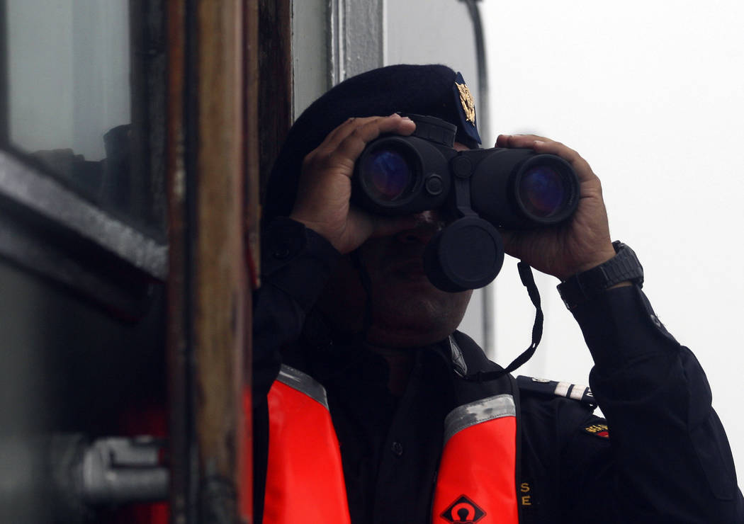 A crew member of a rescue ship uses his binocular during a search operation for the victims of Lion Air plane crash in the waters of Tanjung Karawang, Indonesia, Wednesday, Oct. 31, 2018. A massiv ...