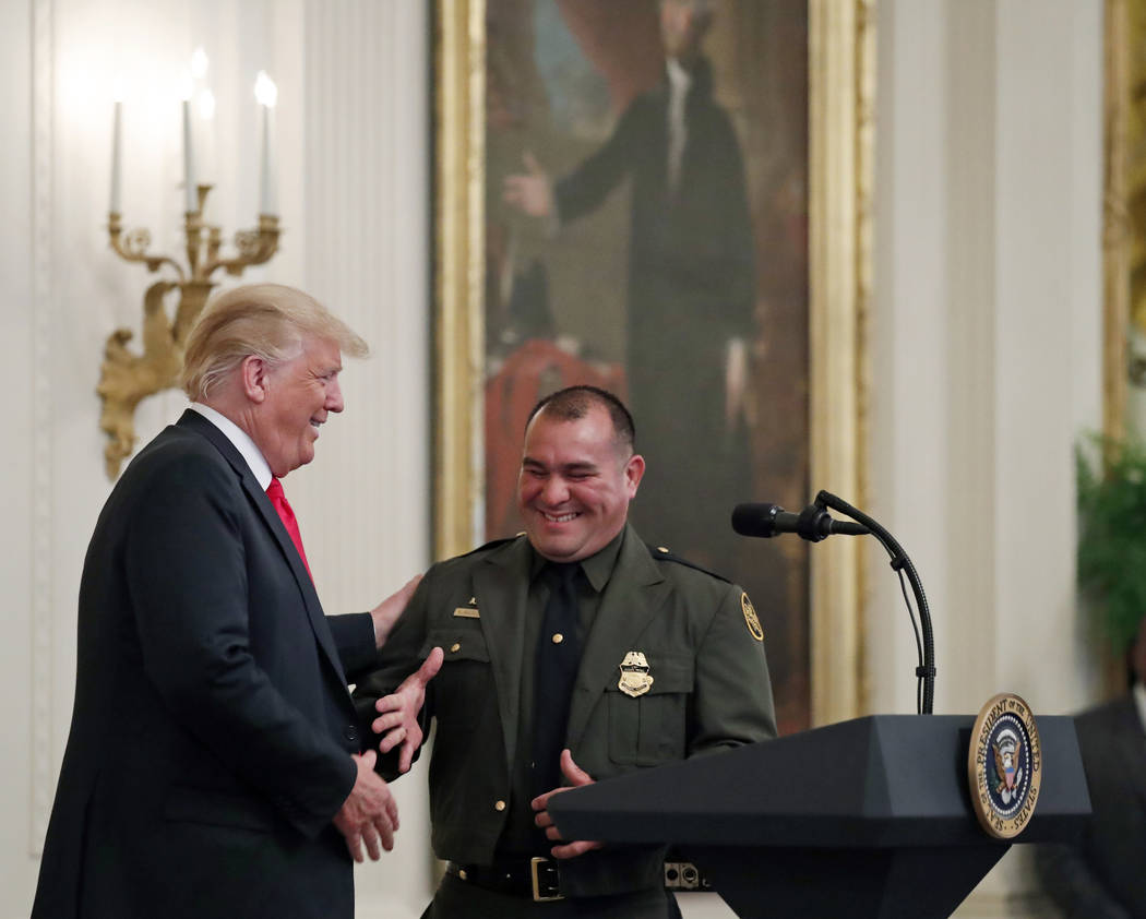 President Donald Trump, left, shakes hands with Customs and Border Patrol agent Adrian Anzaldua, during an event to salute U.S. Immigration and Customs Enforcement (ICE) officers and U.S. Customs ...