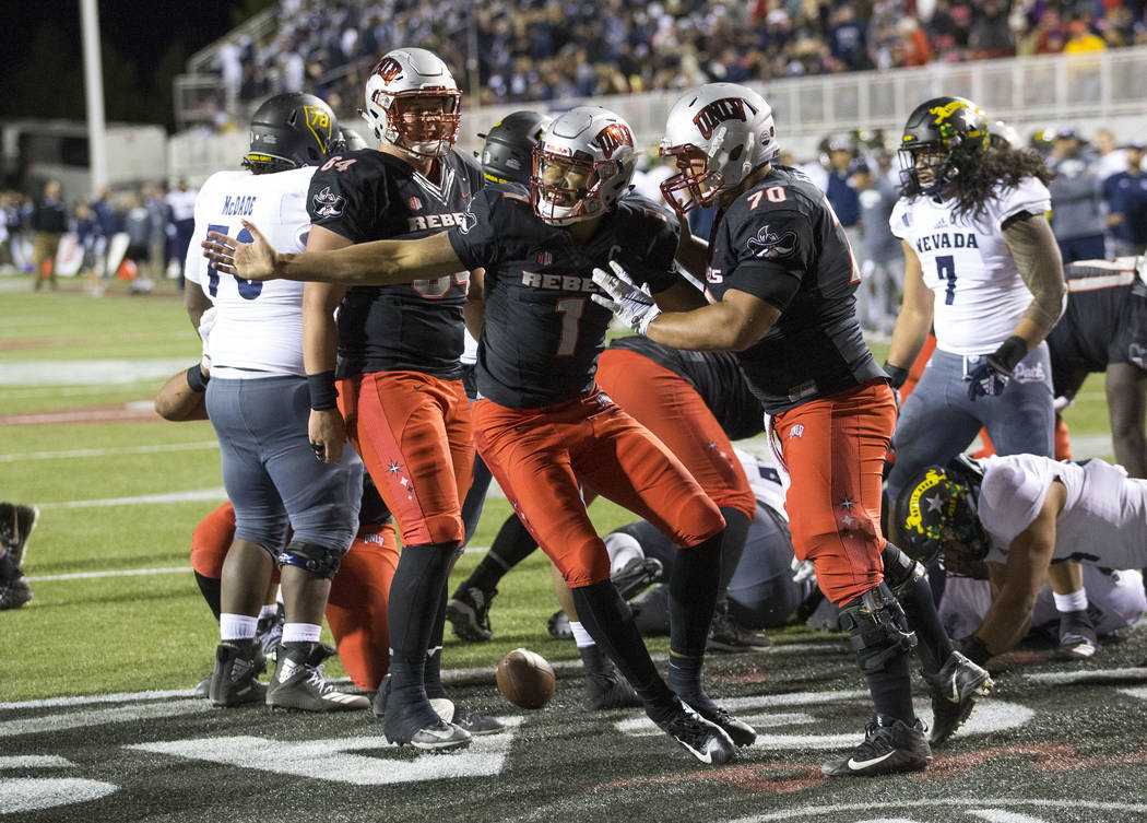 UNLV Rebels quarterback Armani Rogers (1), center, celebrates with offensive lineman Sid Acosta (70) after scoring a touchdown against Nevada Wolf Pack during the second half of an NCAA football g ...