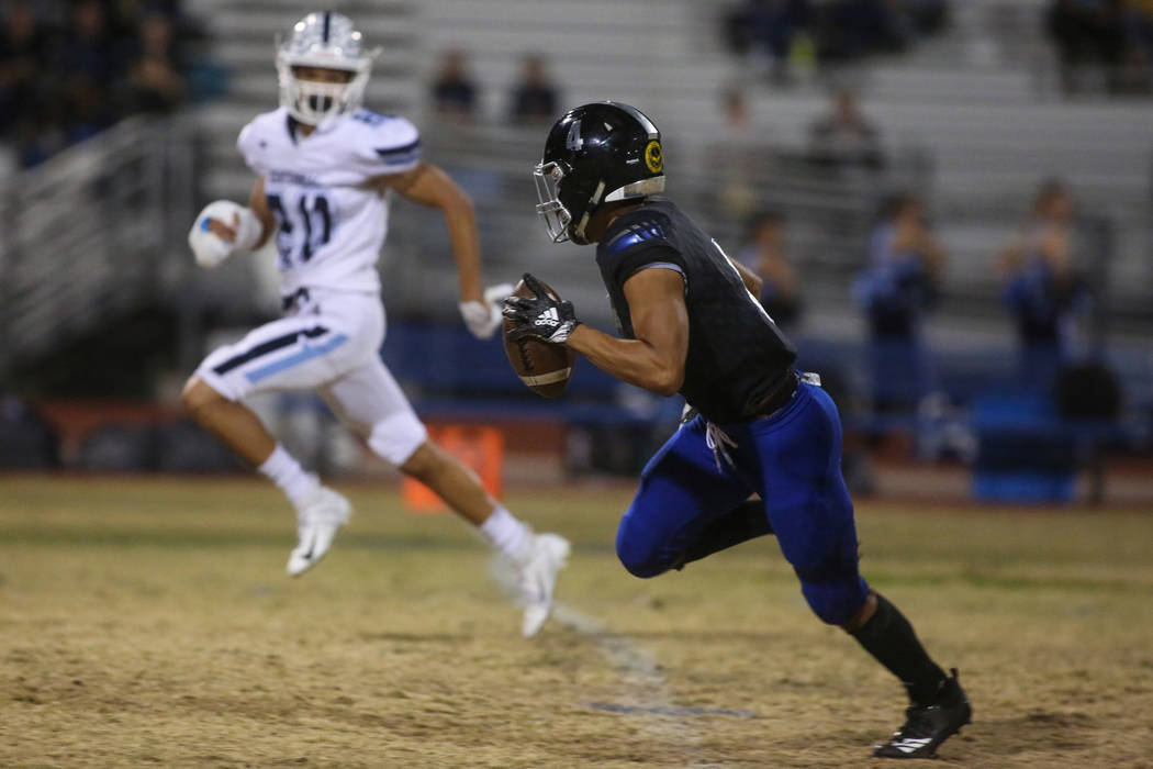 Desert Pines High School's Branden Thomas (4) runs with the ball as Centennial High School's Davone Walden Jr. (20) tries to catch up during the first half of a varsity playoff football game at De ...