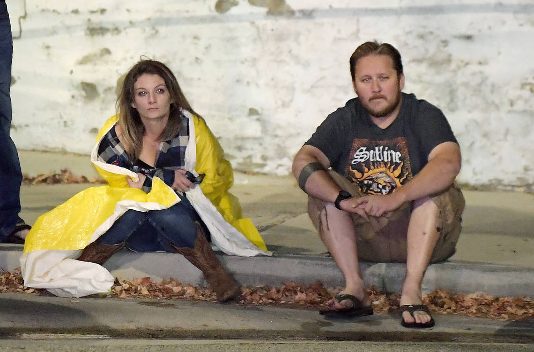 Potential witnesses sit near the scene Thursday, Nov. 8, 2018, in Thousand Oaks, Calif., where a gunman opened fire Wednesday inside a crowded country music bar. (AP Photo/Mark J. Terrill)