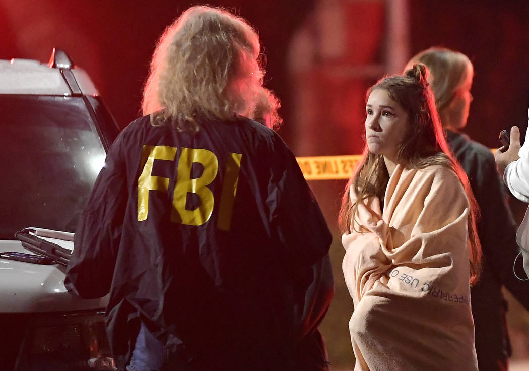 An FBI agent talks to a potential witness as they stand near the scene Thursday, Nov. 8, 2018, in Thousand Oaks, Calif. where a gunman opened fire Wednesday inside a country dance bar crowded with ...
